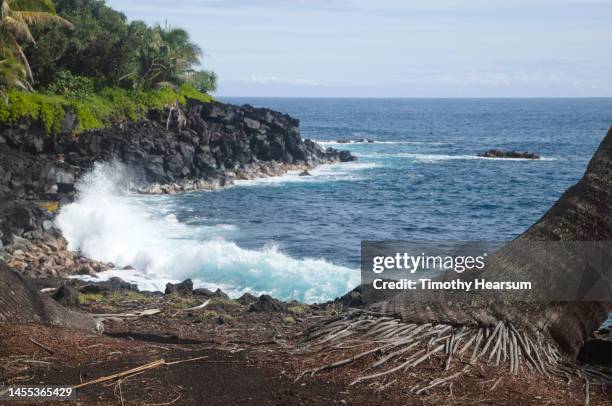 wave crashing in an ocean cove with black lava rock shoreline . - ocean waves crashing into lava rock stockfoto's en -beelden