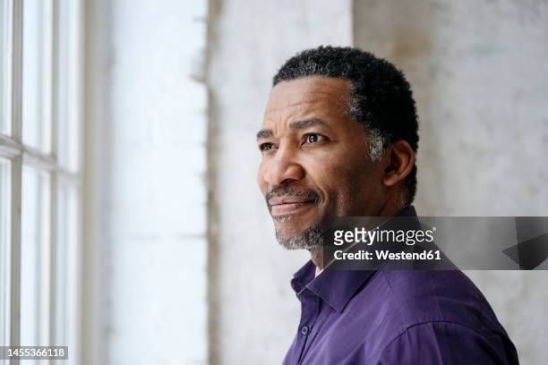 thoughtful mature man looking out through window - black man thinking stock pictures, royalty-free photos & images