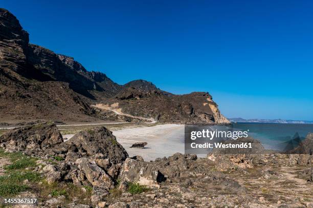 oman, dhofar, salalah, fazayah beach with coastal rocks in foreground - salalah oman stock pictures, royalty-free photos & images