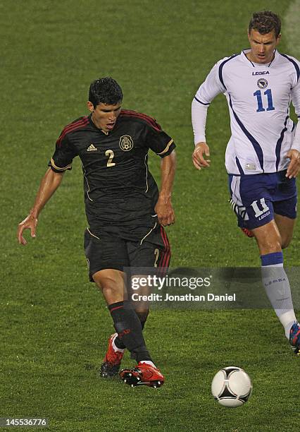 Francisco Rodriguez of Mexico passes under pressure from Edin Dzeko of Bosnia-Herzegovina during an international friendly at Soldier Field on May...