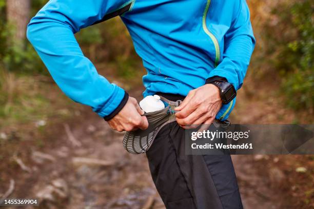 man keeping water bottle in waist pack - waist pack stock pictures, royalty-free photos & images
