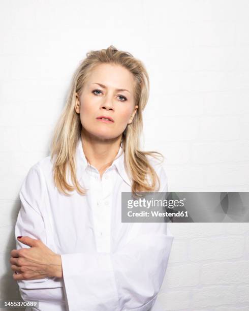 confident blond woman with arms crossed in studio - surexposition effet visuel photos et images de collection