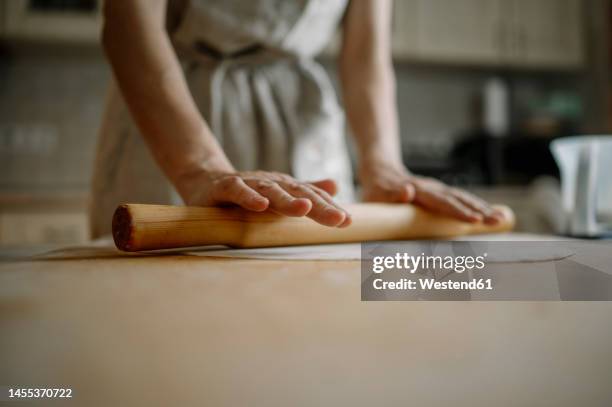 woman rolling dough for dumplings in kitchen at home - surface preparation stock pictures, royalty-free photos & images