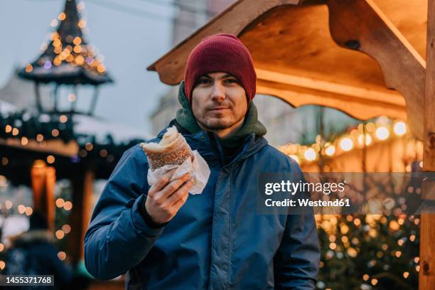 smiling man holding trdelnik at christmas fair - christmas market in poland stockfoto's en -beelden