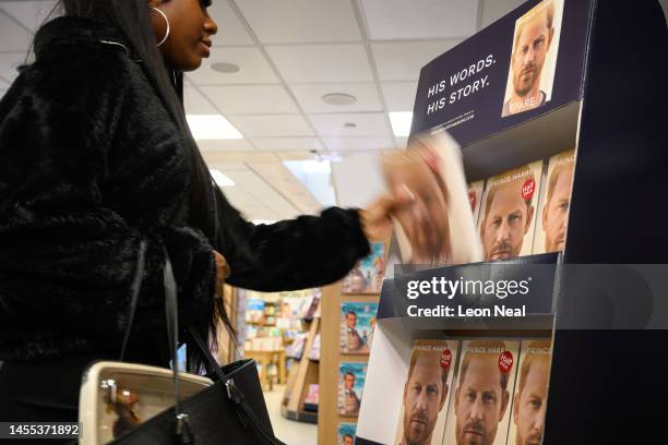 Woman picks up a copy of "Spare" by Prince Harry as they go on sale at one minutes after midnight in WH Smith bookstore at Victoria Station on...