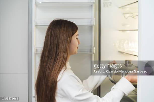teenage girl putting food in the fridge - picking up food stock pictures, royalty-free photos & images