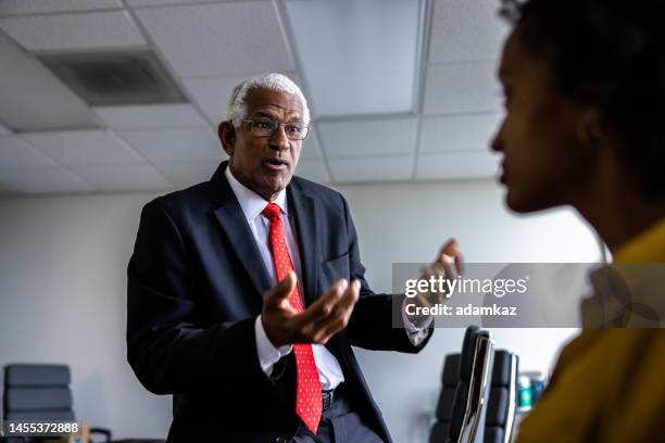 senior black businessman executive and woman using a laptop in conference room - cfo stock pictures, royalty-free photos & images