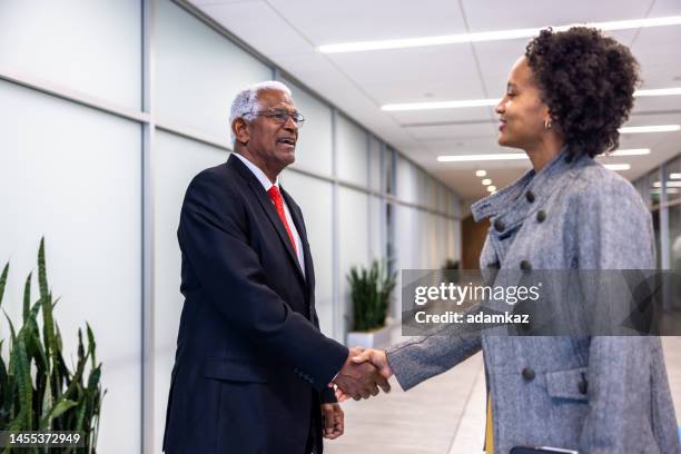 senior black businessman and young woman meeting sharking hands in the hallway - black politician stock pictures, royalty-free photos & images