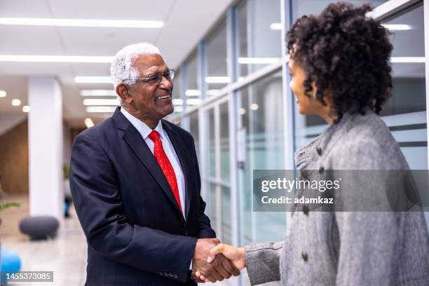 hombre de negocios negro de alto nivel y mujer joven se encuentran con manos de tiburones en el pasillo - candidato fotografías e imágenes de stock