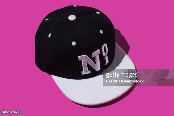 black and white baseball cap with text 'no 1', on pink background. concept of fashion, clothing, accessories, hip hop, baseball, sport, uniform and sun protection. - button sewing item stock-fotos und bilder