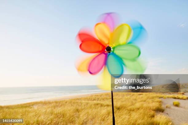 turning pinwheel at dunes by the sea - wind chime stock pictures, royalty-free photos & images