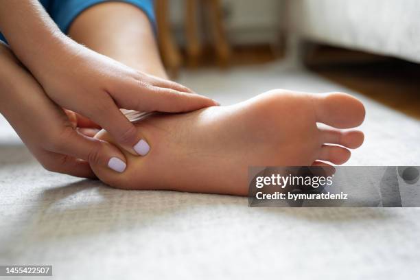 young woman massaging her foot - diabetes feet stock pictures, royalty-free photos & images