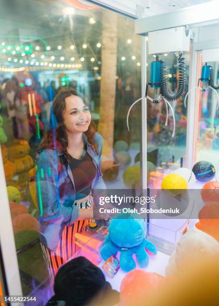 woman playing on claw machine - arcade machine stockfoto's en -beelden