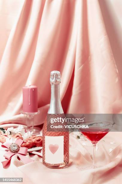 valentine's day composition with champagne bottle , heart and candle at pink fabric background - pink champagne stock pictures, royalty-free photos & images