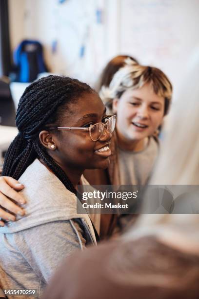 smiling teenage girl wearing eyeglasses sitting by female friends in group therapy - teen group therapy stock pictures, royalty-free photos & images