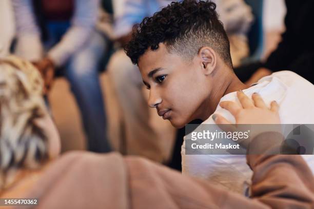 teenage boy looking at female friend consoling in group therapy - alleen tieners stockfoto's en -beelden