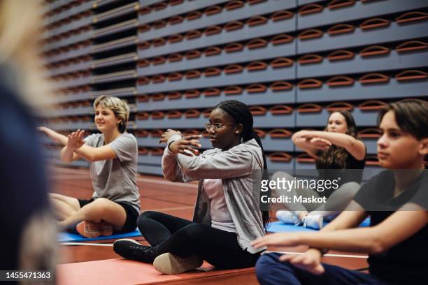 teenage girls and boy gesturing while practicing yoga in sports court - teenager yoga stock pictures, royalty-free photos & images