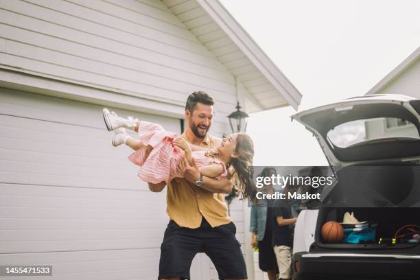 happy father playing with daughter by electric car outside house - happy family home outdoors stockfoto's en -beelden