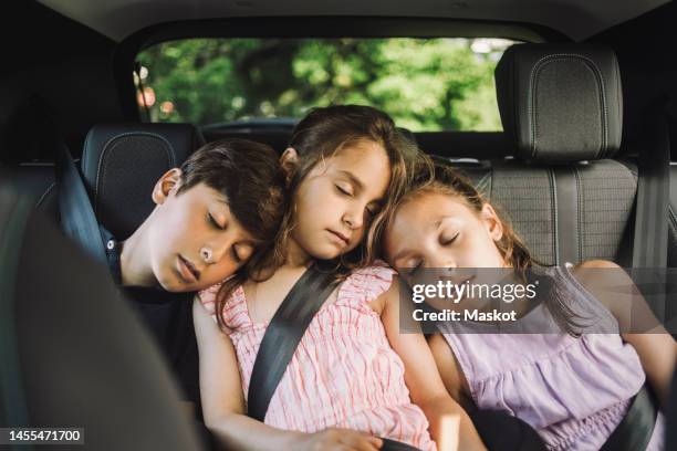 tired siblings sleeping on back seat while traveling in car - three people in car stock pictures, royalty-free photos & images
