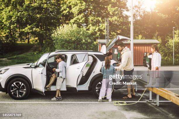 family charging electric car at station - elektrische auto stockfoto's en -beelden