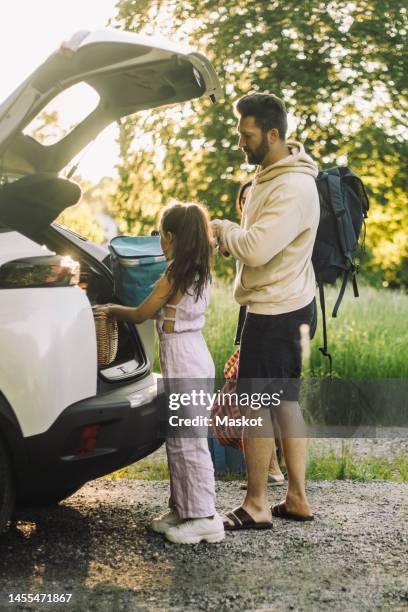 side view of daughter and father unloading luggage from car trunk - car picnic stock pictures, royalty-free photos & images