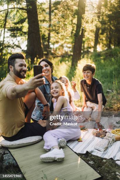 father taking selfie with family through smart phone during picnic - europe de l'ouest photos et images de collection