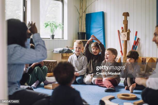 female child care worker teaching boys and girls in day care center - nursery stock-fotos und bilder