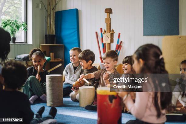 happy multiracial male and female students enjoying while playing drum kit in child care center - モンテッソーリ教育 ストックフォトと画像
