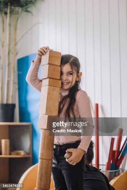 smiling girl stacking wooden toy blocks in kindergarten - モンテッソーリ教育 ストックフォトと画像