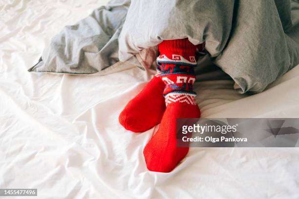 feet wearing red knitted socks under a blanket - lower bildbanksfoton och bilder