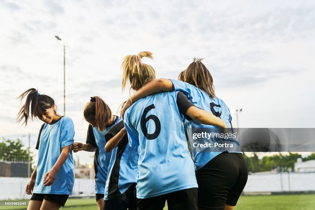 Girls football players hugging on field after scoring a goal on field