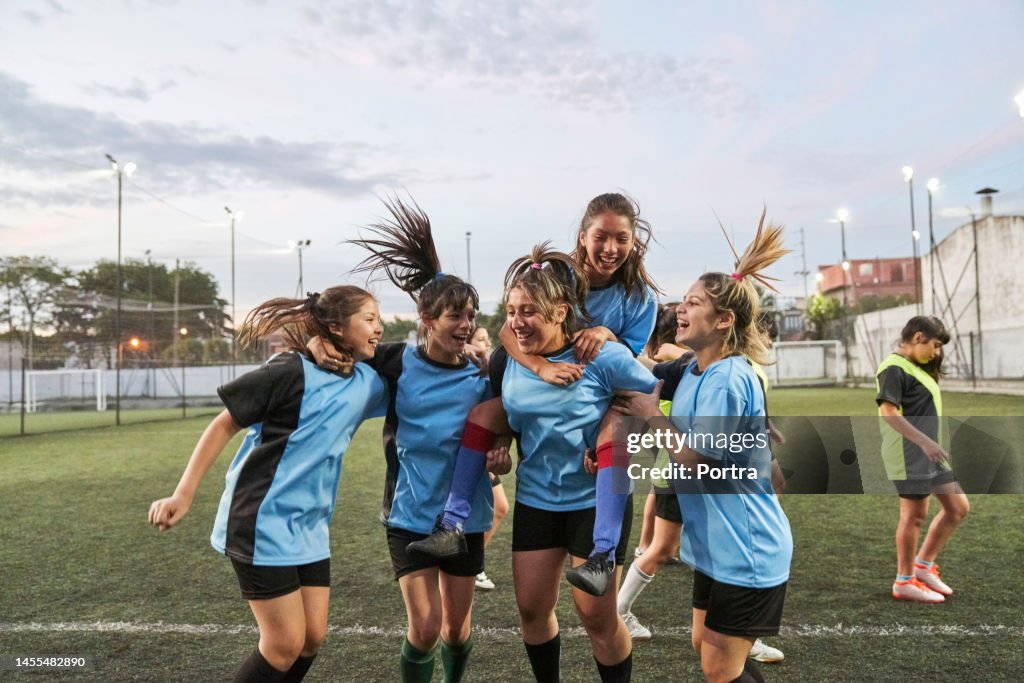 Cheerful girls soccer team celebrating after winning match