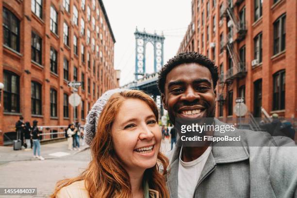 a multi-ethnic couple is taking a selfie in the brooklyn with manhattan bridge in the background - valentines african american 個照片及圖片檔