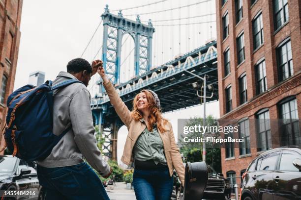 a multi-ethnic couple is dancing in brooklyn with manhattan bridge in the background - american musical duo stock pictures, royalty-free photos & images