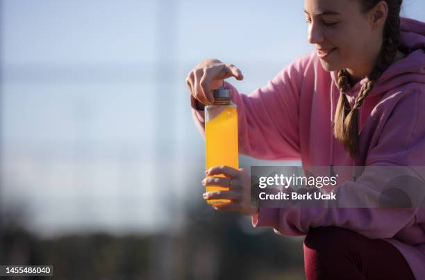 young woman is hydrating during outdoor exercise in on the outside. - sports drink stock pictures, royalty-free photos & images