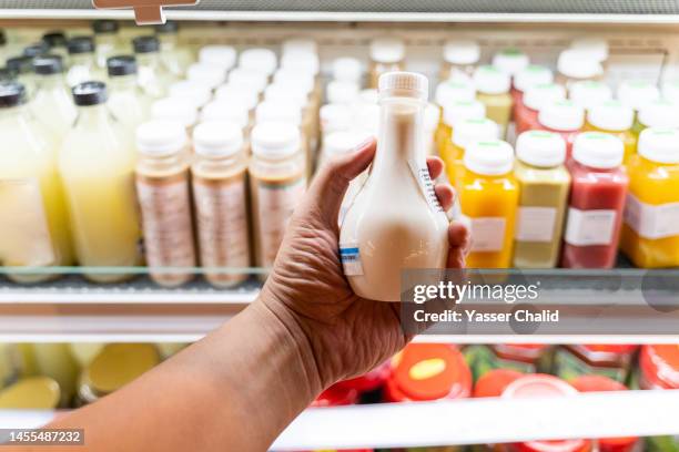 hand holding fresh goat milk in a market - milk bottle stock-fotos und bilder