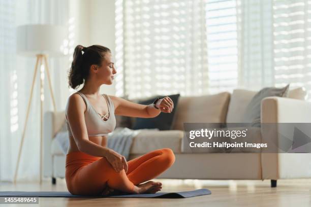 young woman taking exercise in her living room. - reloj inteligente fotografías e imágenes de stock