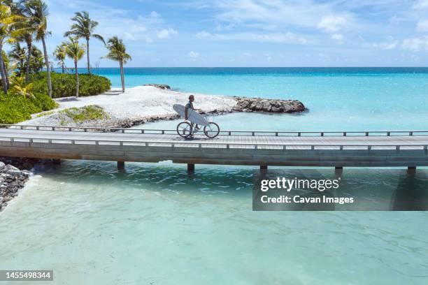 aerial view of young man riding by bicycle on jetty in the sea - thulusdhoo stock pictures, royalty-free photos & images