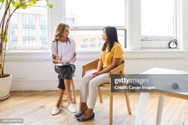 female patient taking advice from general practitioner in clinic - doctor general practitioner stock pictures, royalty-free photos & images