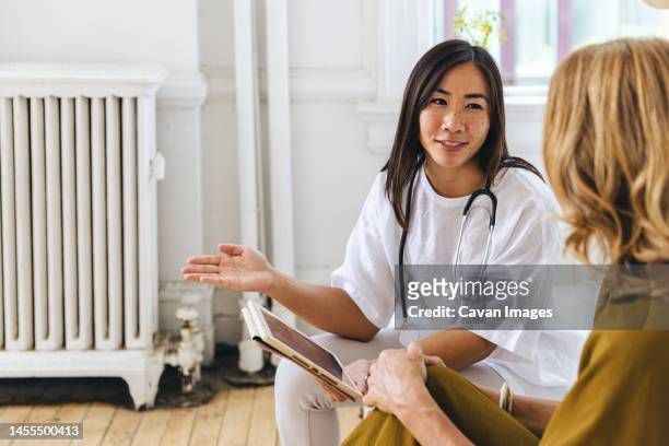 smiling doctor discussing with female patient at clinic - bezoek stockfoto's en -beelden