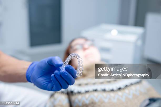 hands of dentist holding dental aligner. - invisalign stockfoto's en -beelden