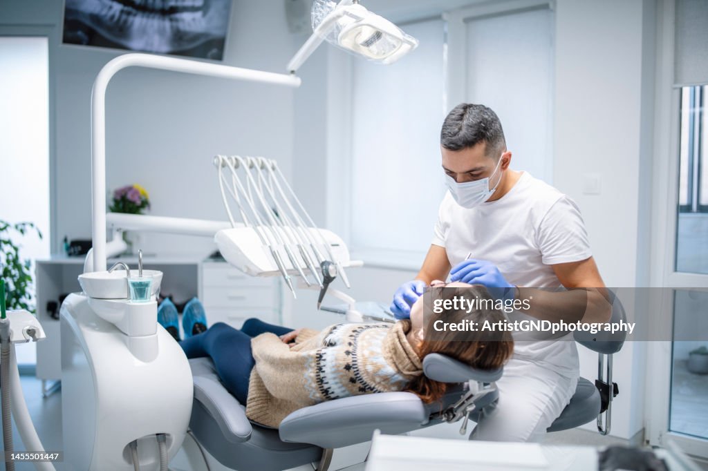 Dentist examining female patient.