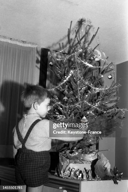 Enfant décorant le sapin de noël, dans les années 1950.