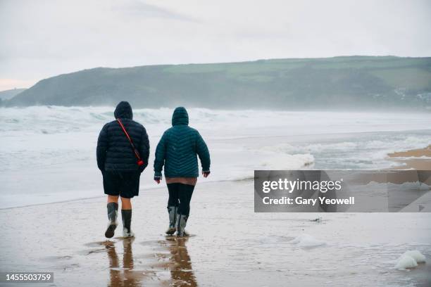 a couple walking on a beach in the rain - shower stock pictures, royalty-free photos & images
