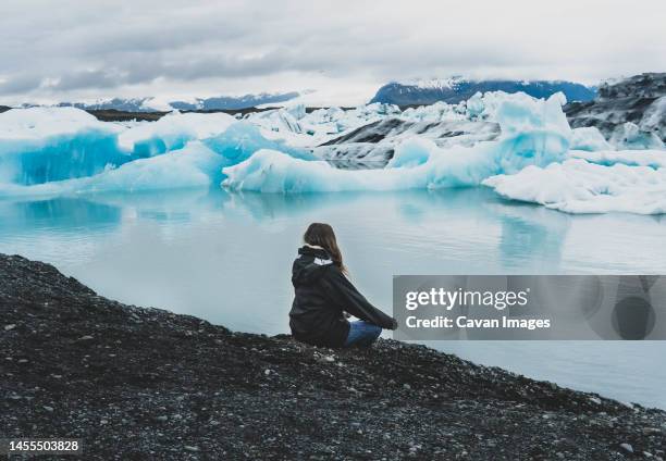 woman meditating near lake with iceberg - glaciar lagoon imagens e fotografias de stock