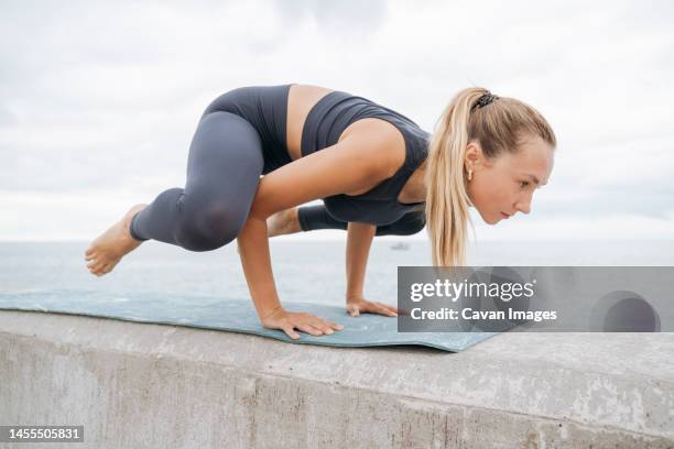 a girl on the seashore doing yoga frog pose - woman frog hand stock-fotos und bilder