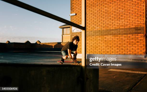 man skateboarding on the top of a building at sunset - longboard skating stock pictures, royalty-free photos & images