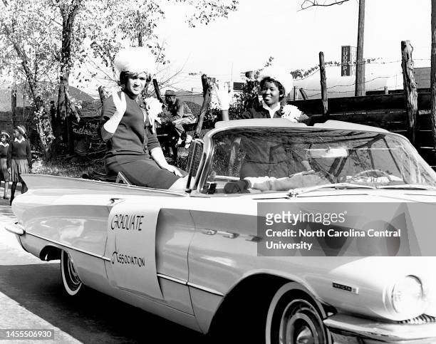 Miss Homecoming and runner-up of Graduate Association waving hands while sitting in car during procession on street at North Carolina Central...