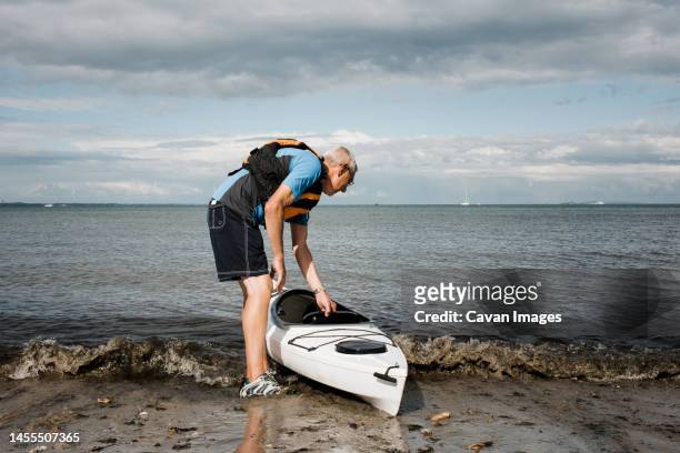 retired man heading out into the sea to exercise in a kayak - summer heading stock pictures, royalty-free photos & images