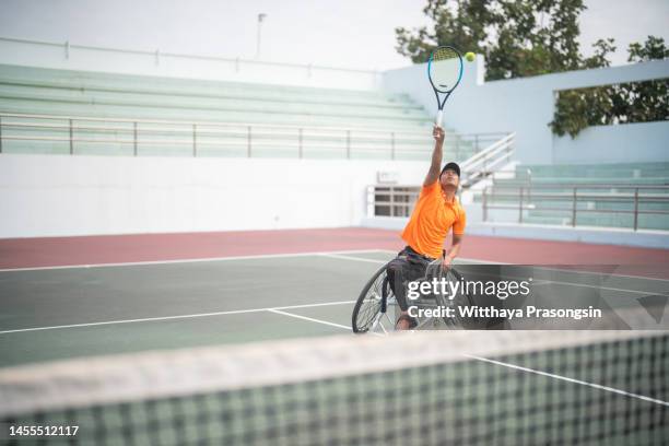 disabled man in wheelchair playing tennis on tennis court - wheelchair tennis stock pictures, royalty-free photos & images